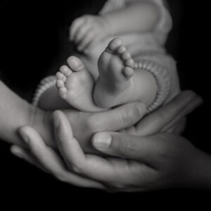 Babyfüsschen auf Händen der Eltern mit schwarzem Hintergrund in schwarz/weiss