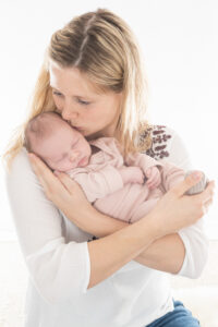 Neugeborenenfoto mit Mutter vor weissem Hintergrund