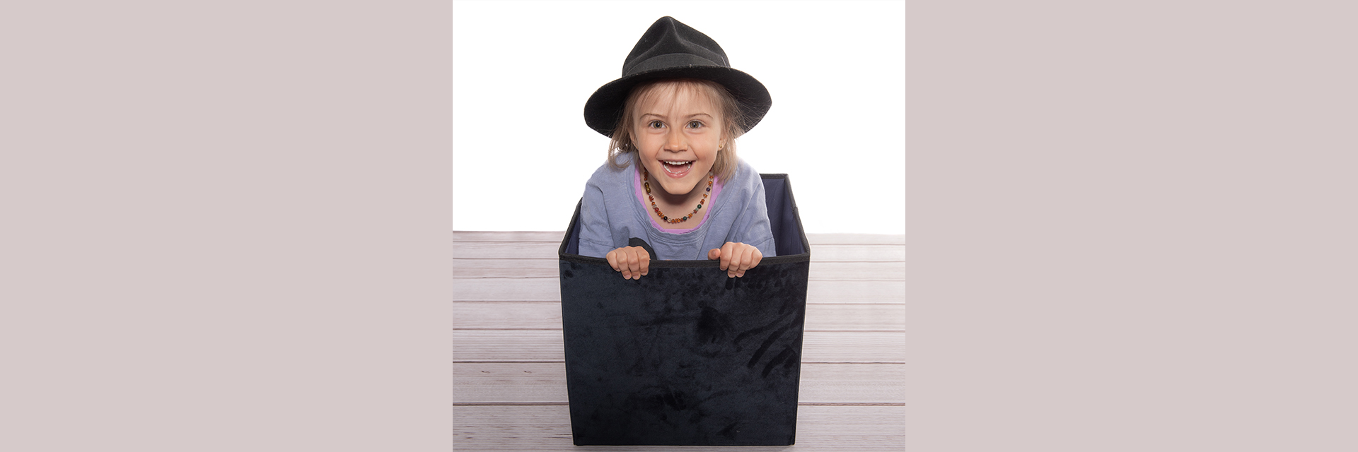 Fröhliches Mädchen sitzt in der Kiste beim Kindershooting