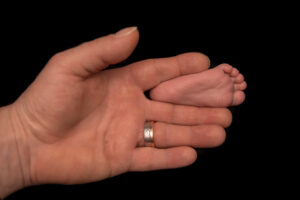 Newbornfüsschen mit Hand von Vater beim Shooting für Neugeborenenfotos