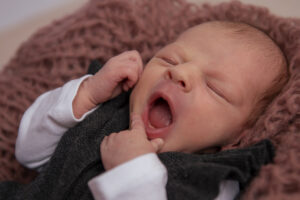 Baby beim gähnen mit Hand am Kinn am Newbornshooting