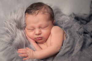 Schlafendes Baby auf grauem Fell an Neugeborenenshooting