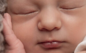 Gesicht von Baby mit Hand an der Wange beim Newbornshooting