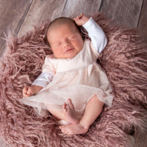 Newbornshooting mit schlafendem Baby auf rosa Fell